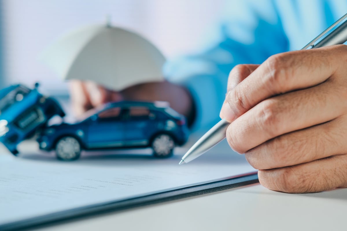 Reviewing an auto insurance claim form beside a model car